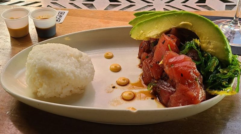 Plate of seared tuna with sliced avocado, seaweed salad, and white rice